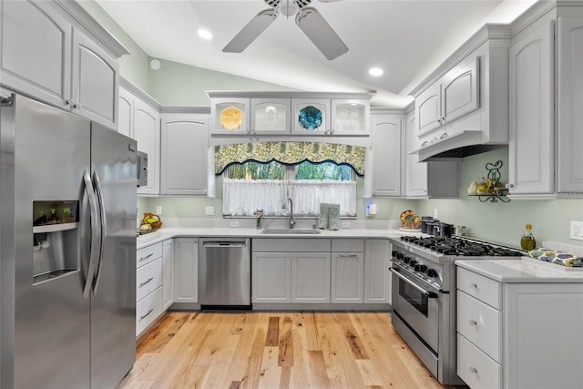 kitchen with vaulted ceiling, light countertops, appliances with stainless steel finishes, and a sink