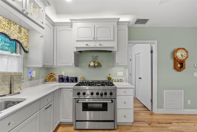 kitchen with light wood-type flooring, visible vents, stainless steel stove, and light countertops