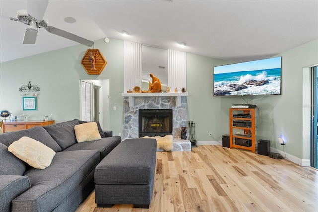 living area featuring light wood-style flooring, a fireplace, baseboards, and lofted ceiling