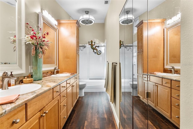 full bath with double vanity, toilet, wood finished floors, and a sink