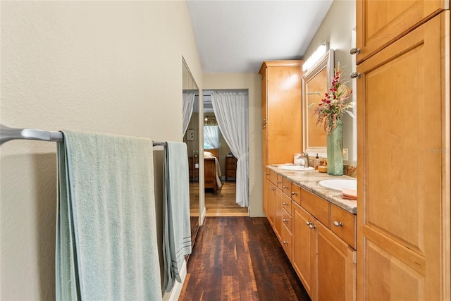 full bath featuring double vanity, a sink, and wood finished floors