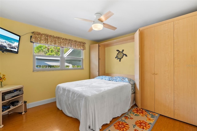 bedroom with a ceiling fan, light wood-type flooring, and baseboards