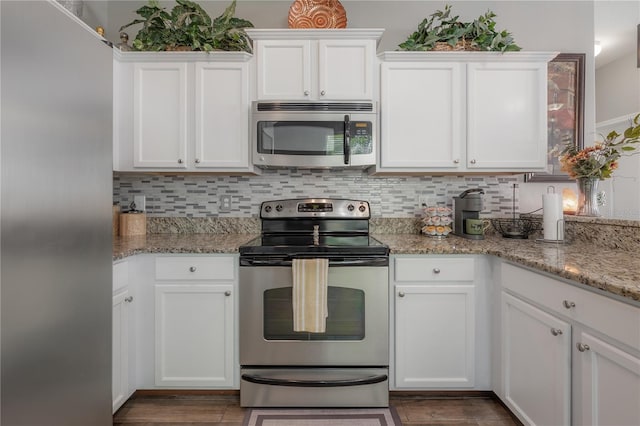 kitchen with light stone counters, backsplash, appliances with stainless steel finishes, and white cabinetry