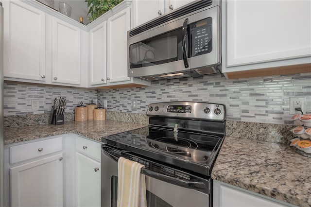 kitchen featuring white cabinets, light stone countertops, tasteful backsplash, and stainless steel appliances