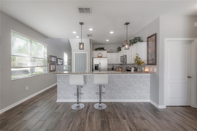 kitchen with visible vents, appliances with stainless steel finishes, a peninsula, and dark wood finished floors