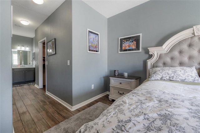 bedroom featuring a sink, baseboards, dark wood finished floors, and ensuite bathroom