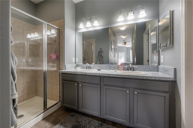 full bathroom featuring a sink, wood finished floors, a stall shower, and double vanity