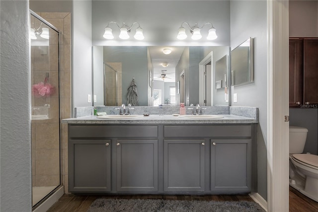 full bathroom featuring double vanity, toilet, a stall shower, and a sink