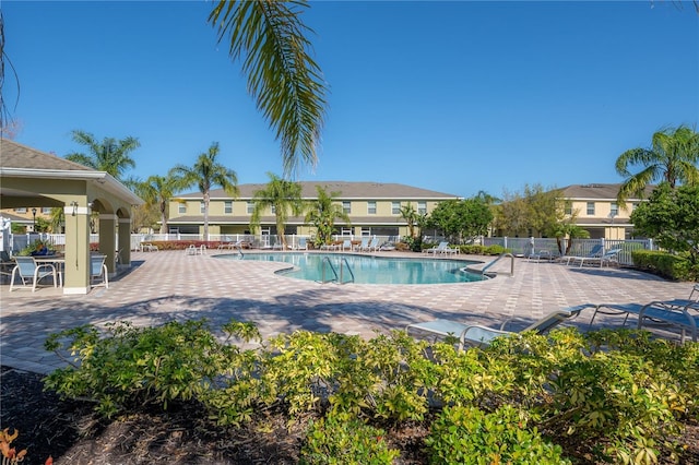 community pool with a patio and fence