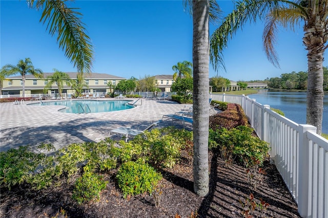 pool with a patio, a water view, and fence