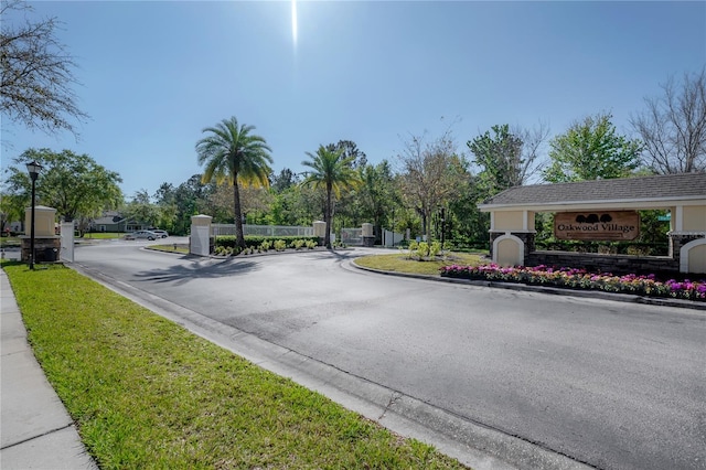 view of road with curbs, a gated entry, and street lighting