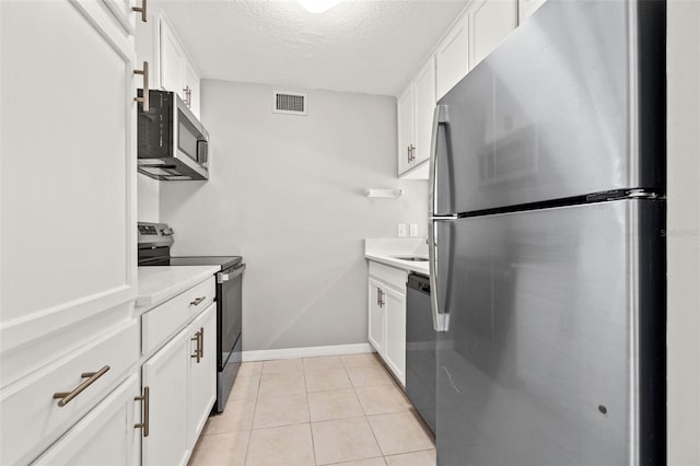 kitchen with light tile patterned floors, visible vents, appliances with stainless steel finishes, and white cabinetry