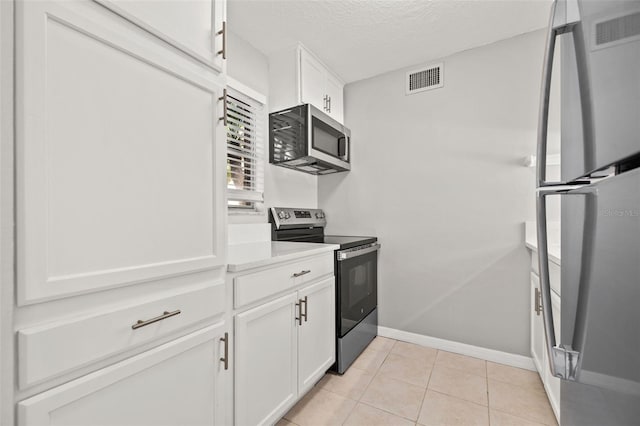 kitchen featuring visible vents, light tile patterned floors, stainless steel appliances, white cabinets, and a textured ceiling