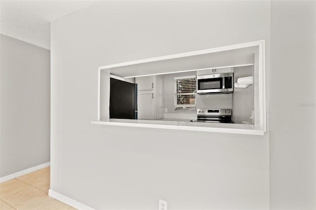 kitchen with tile patterned floors, baseboards, and stainless steel appliances