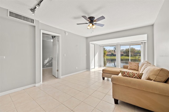 living area with light tile patterned flooring, a ceiling fan, visible vents, and baseboards