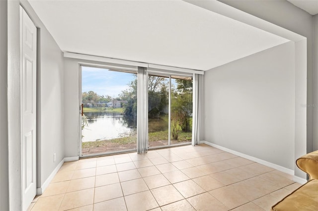 unfurnished room featuring a wall of windows, light tile patterned floors, and baseboards