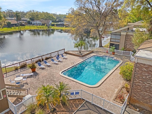 pool featuring a patio area, fence, and a water view