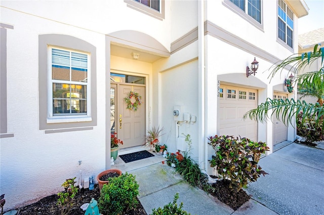 entrance to property with stucco siding, an attached garage, and concrete driveway