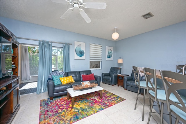 living area featuring light tile patterned flooring, visible vents, and a textured ceiling