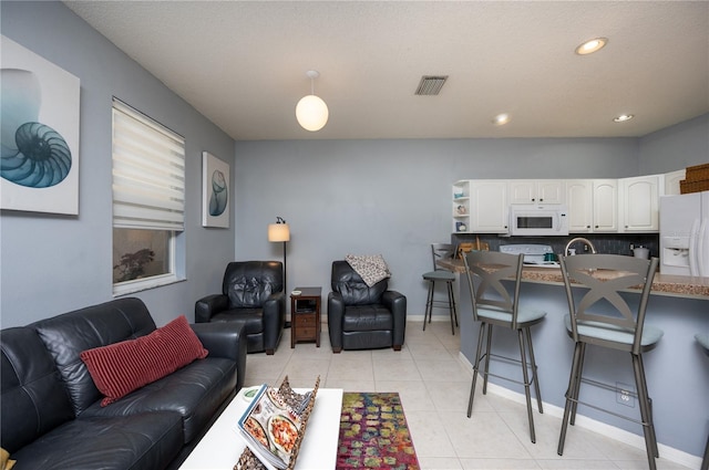 living area featuring light tile patterned flooring, recessed lighting, visible vents, and baseboards