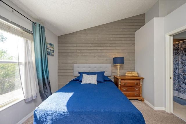 carpeted bedroom featuring vaulted ceiling, multiple windows, wood walls, and a textured ceiling