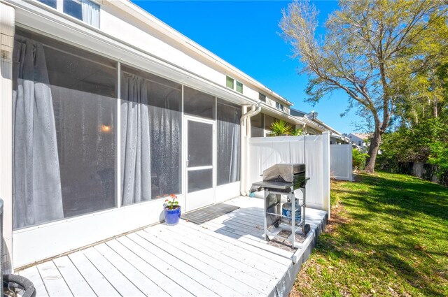 wooden terrace featuring a yard, fence, a grill, and a sunroom