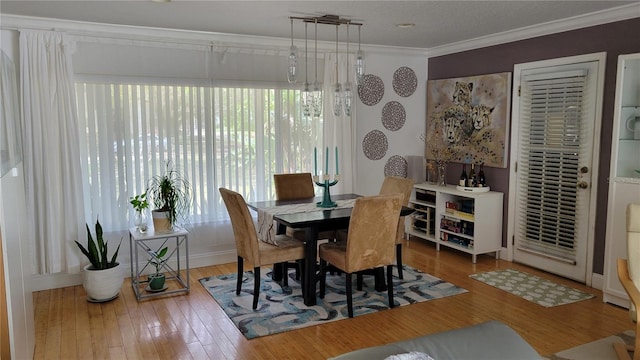 dining space with wood finished floors and crown molding