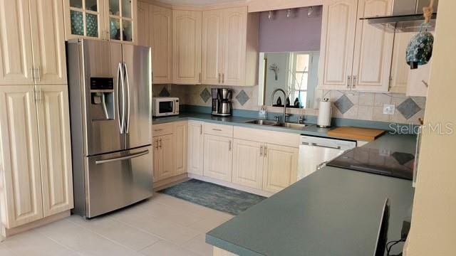 kitchen with a sink, backsplash, dark countertops, white appliances, and glass insert cabinets