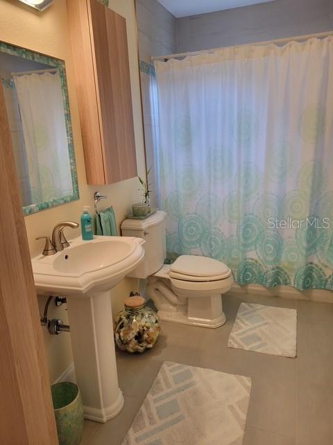 bathroom featuring tile patterned flooring, toilet, and shower / bath combo