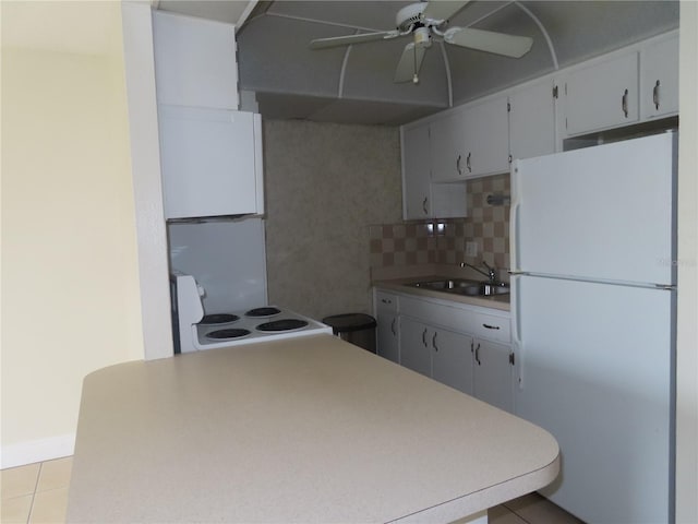 kitchen featuring backsplash, light countertops, light tile patterned floors, white appliances, and a sink