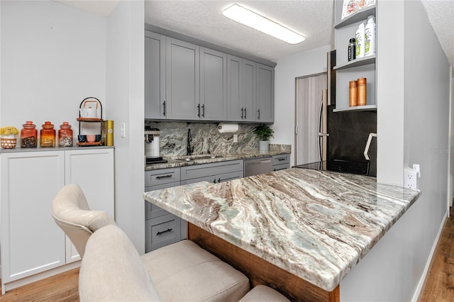 kitchen featuring a sink, open shelves, dishwasher, and gray cabinetry