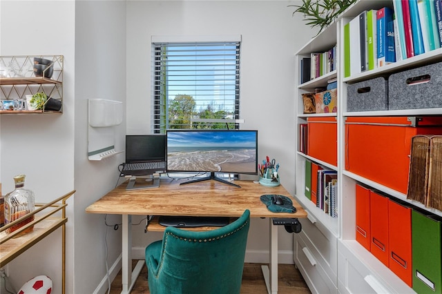 office space with built in desk, baseboards, and wood finished floors