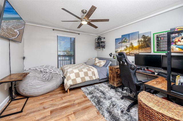 bedroom with ceiling fan, wood finished floors, and a textured ceiling