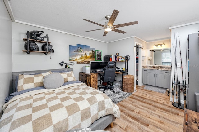 bedroom featuring a walk in closet, ensuite bathroom, a ceiling fan, crown molding, and light wood finished floors