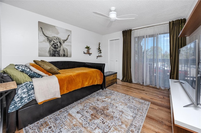 bedroom with a textured ceiling, wood finished floors, and a ceiling fan