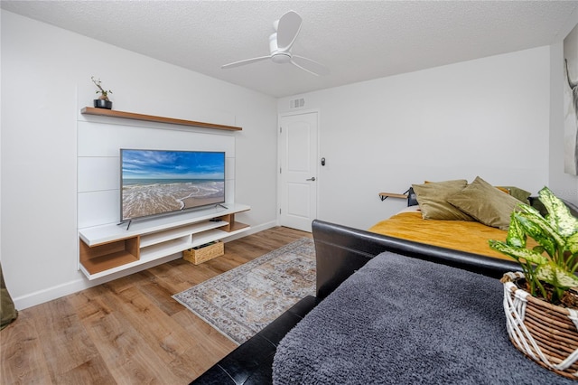 living room featuring visible vents, a textured ceiling, ceiling fan, and wood finished floors