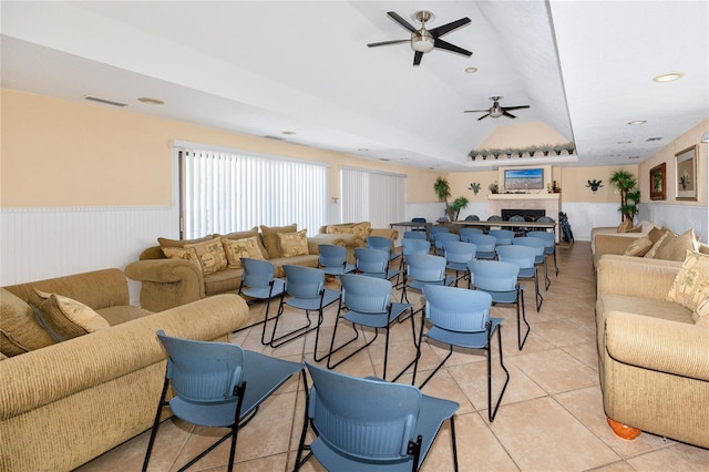 living area featuring light tile patterned floors, a wainscoted wall, visible vents, and ceiling fan