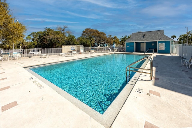 community pool with a patio area and fence