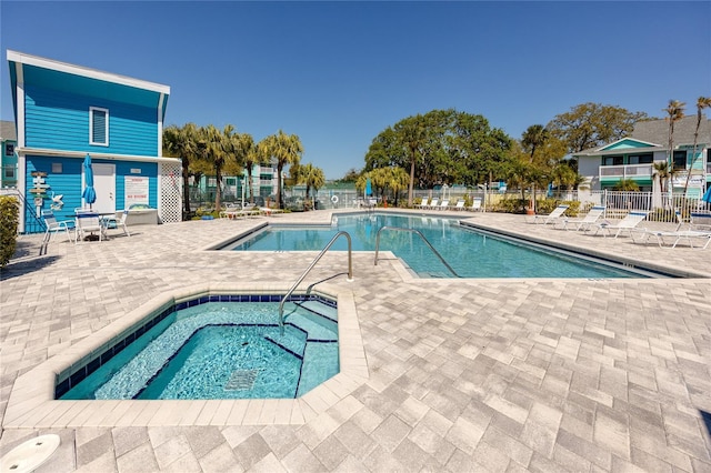 pool featuring a patio area, a community hot tub, and fence