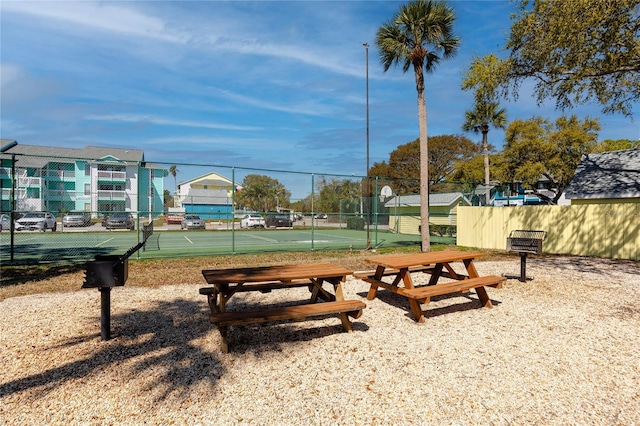 surrounding community with a tennis court and fence