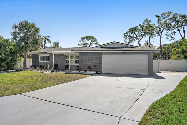 view of front of house featuring a front yard, a gate, fence, concrete driveway, and a garage