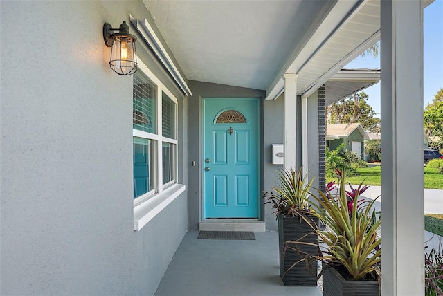 view of exterior entry featuring stucco siding and a porch