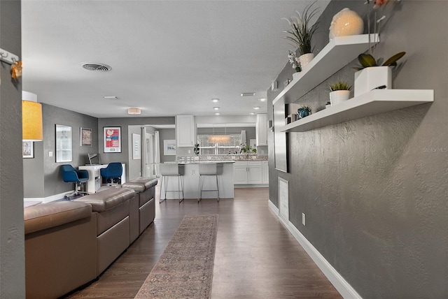 living room featuring visible vents, baseboards, and dark wood-style flooring