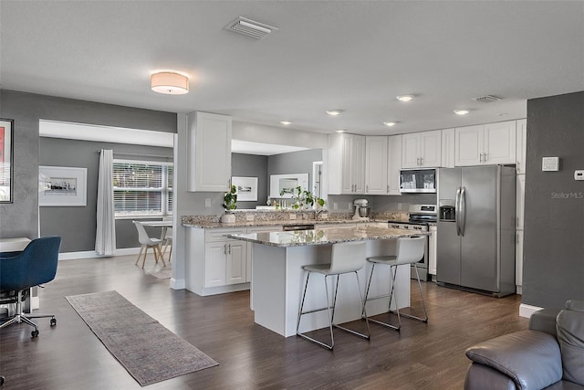 kitchen with a center island, visible vents, white cabinetry, and stainless steel appliances