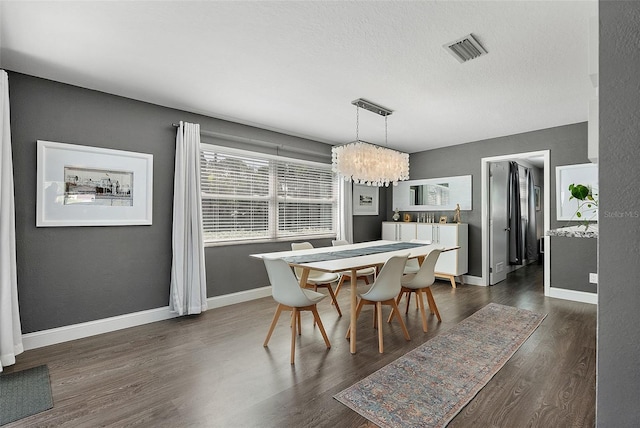 dining room featuring visible vents, baseboards, an inviting chandelier, a textured ceiling, and dark wood-style flooring