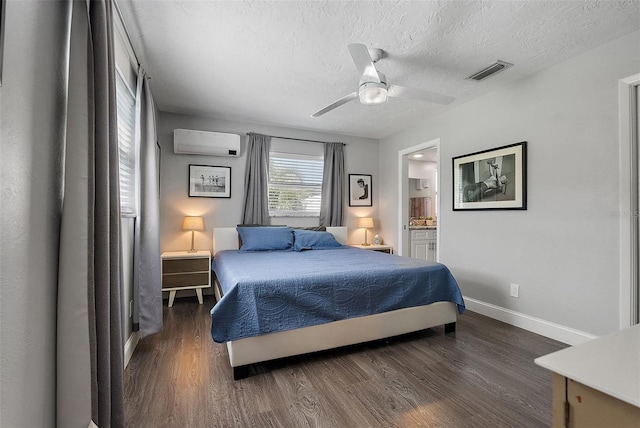 bedroom featuring visible vents, a textured ceiling, wood finished floors, a wall unit AC, and baseboards