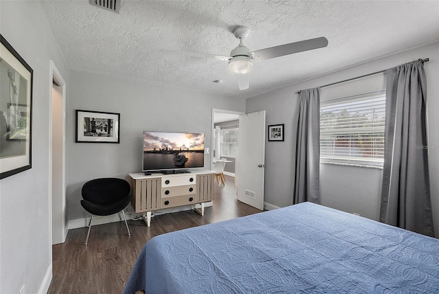 bedroom with visible vents, a textured ceiling, baseboards, and wood finished floors