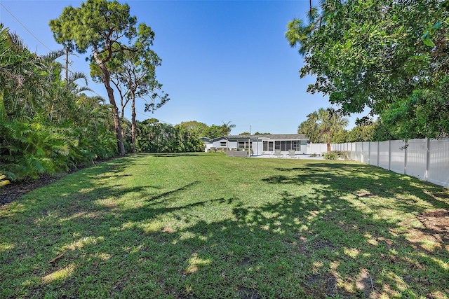 view of yard featuring a fenced backyard and a sunroom