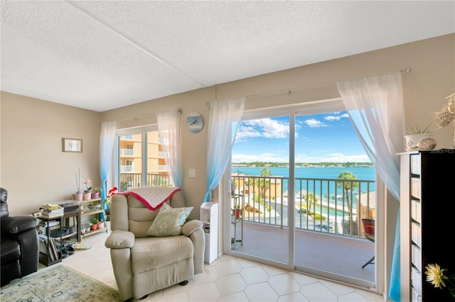 living area featuring a water view and a textured ceiling