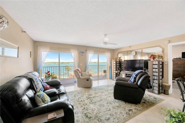 living area with a ceiling fan and a textured ceiling